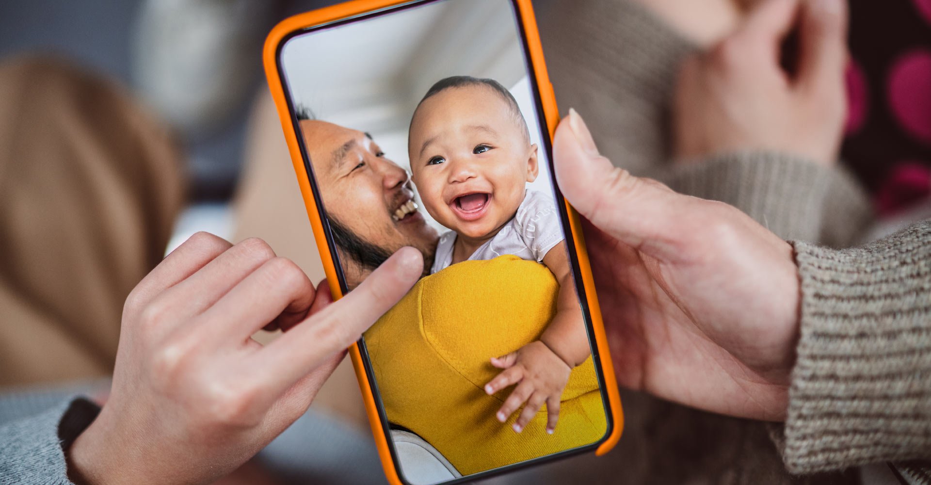 Handy-Bildschirm, der ein Kleinkind auf dem Arm seines Papas zeigt.